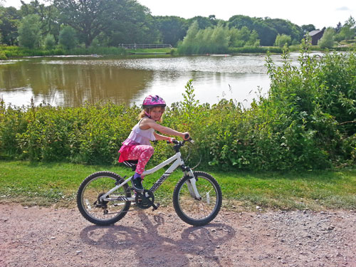 Girl on mountain bike by lake www.FranglaiseMummy.com