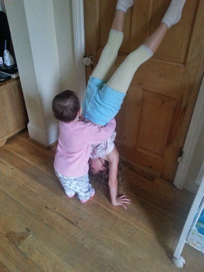 Toddler hugging sister doing handstand l Why it's good to ignore your kids l www.FranglaiseMummy.com l French and English Parenting and Lifestyle Ramblings